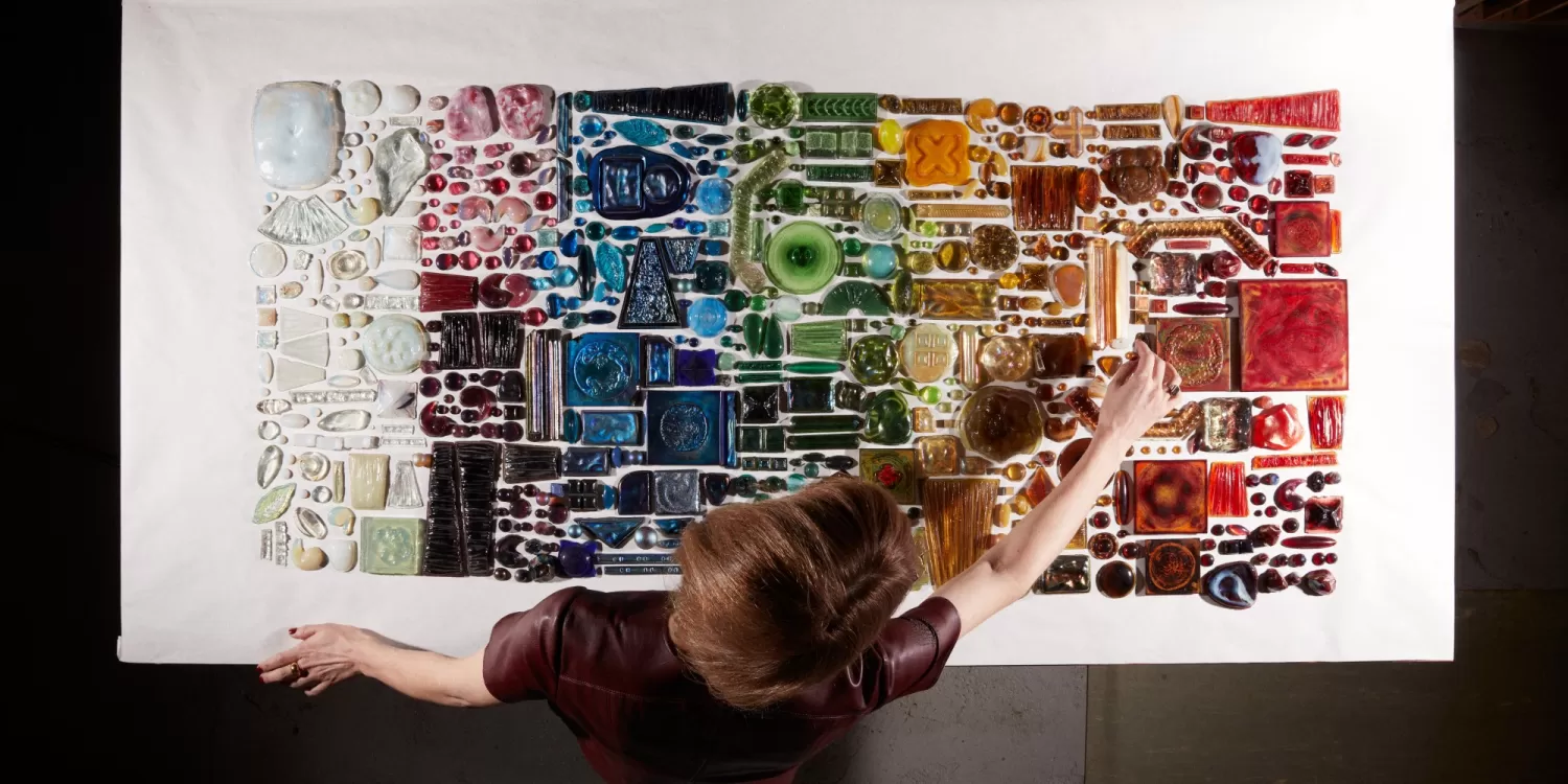 Curator arranging pressed-glass jewels in a rainbow gradation