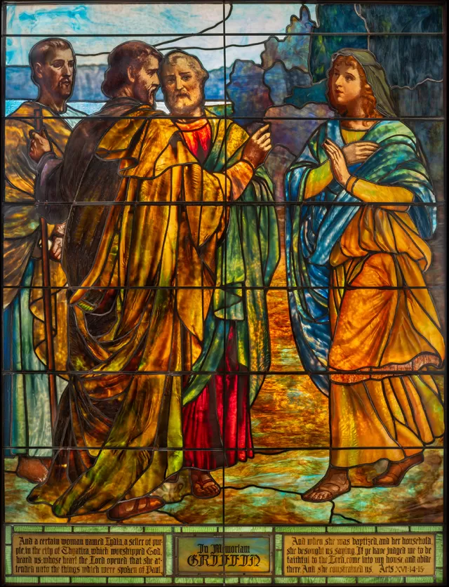 Vertical Tiffany stained glass window depicting Lydia Entertaining Christ and the Apostles